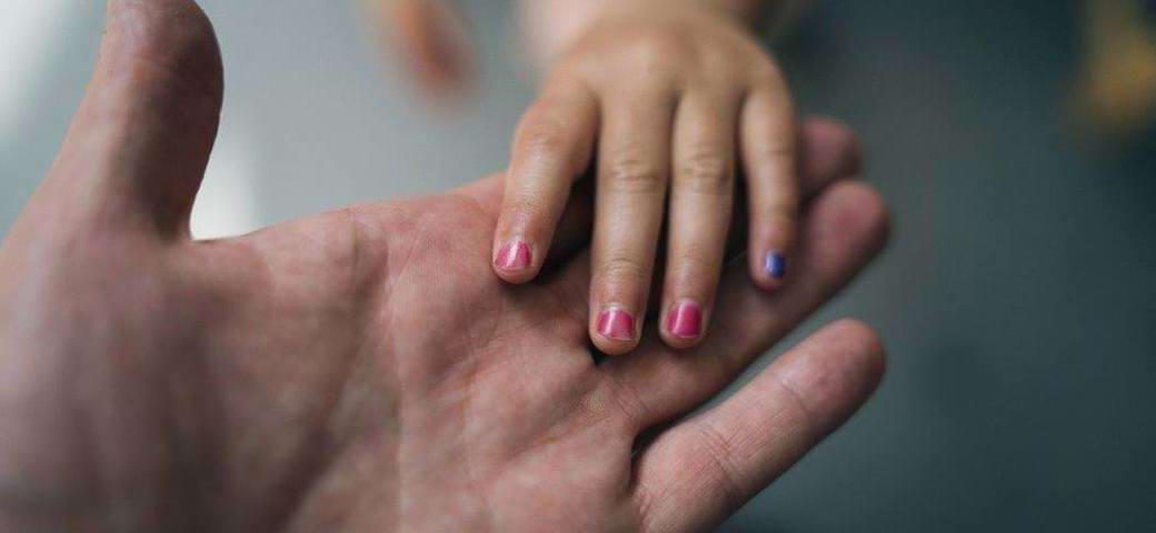 Barns hånd med neglelak, i en voksens hånd