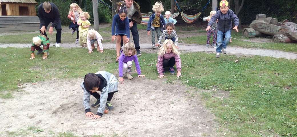 Børn hopper som frø på legepladsen