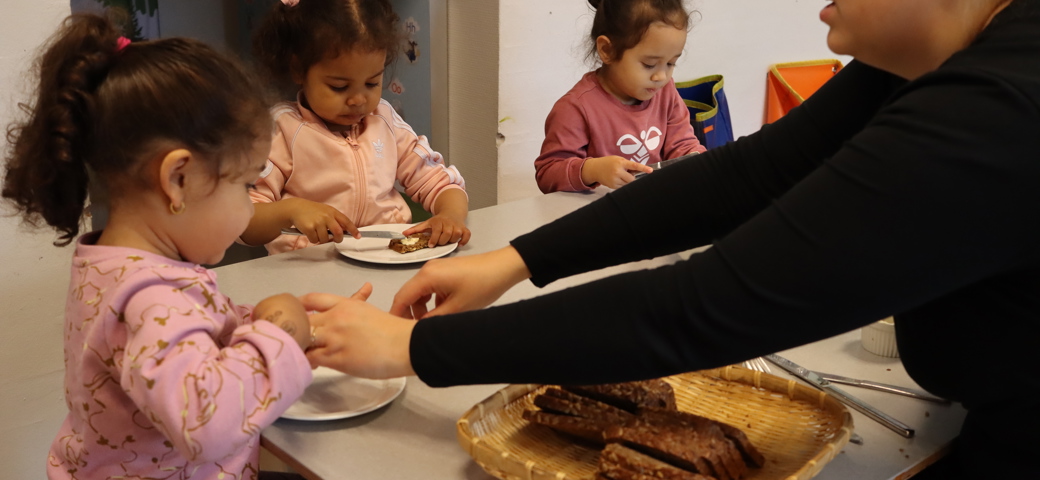 Børnene lærer selv at hælde vand op og smøre brødet - vi giver en hjælpende hånd, når der er brug for det